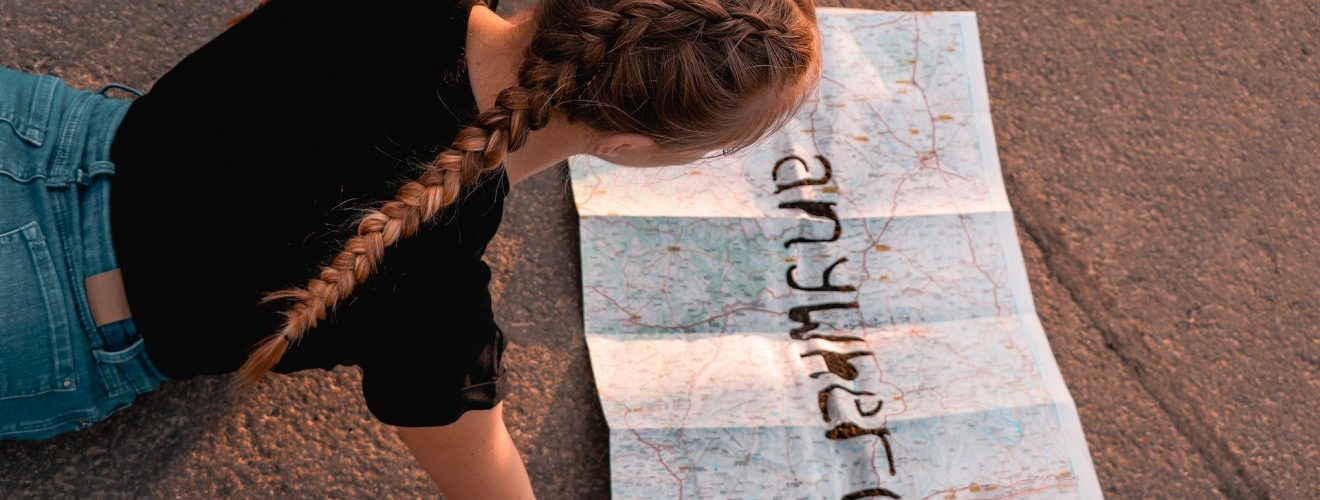 Mädchen, das eine Landkarte studiert, auf der in fetten Buchstaben "anywhere" steht