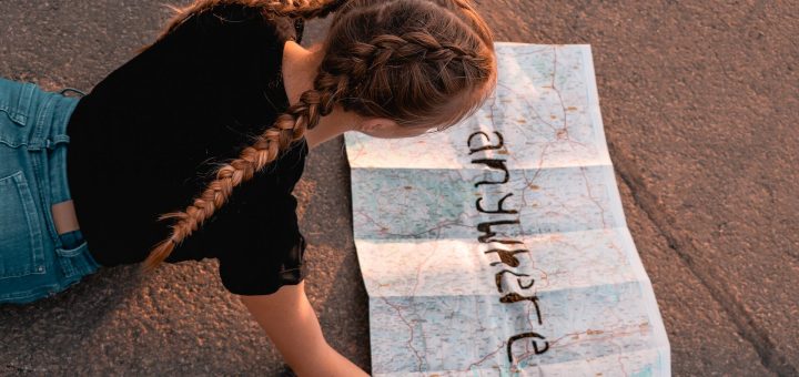 Mädchen, das eine Landkarte studiert, auf der in fetten Buchstaben "anywhere" steht